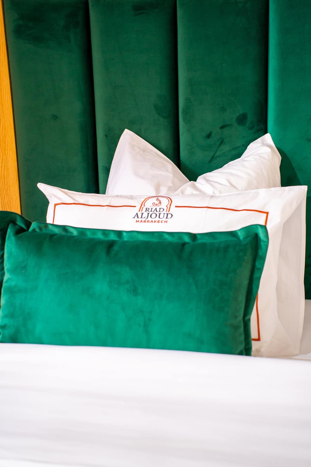 Coussin en velours émeraude et oreillers brodés au logo du riad