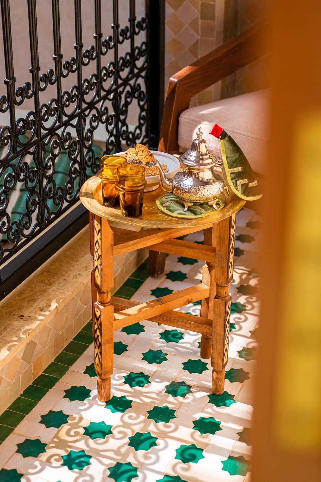 Théière argentée et verres ambrés sur une petite table près de la galerie du riad
